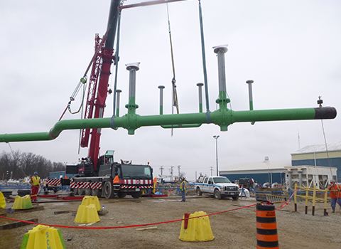 Crane lifting pipes and valve assembly on civil construction site