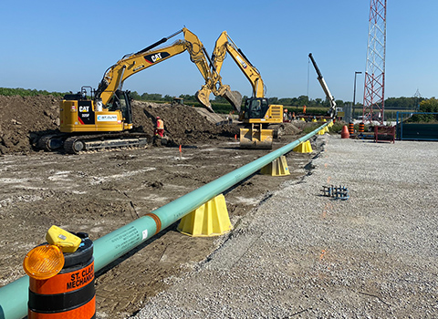 Large pipeline being buried by excavators